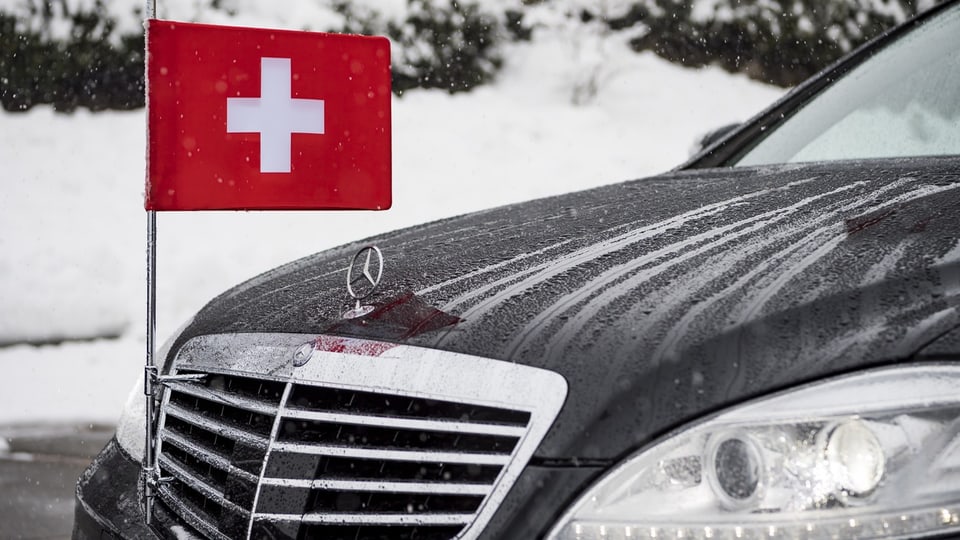 Vorderteil eines schwarzen Mercedes mit einer rot-weissen Schweizflagge eingehängt.