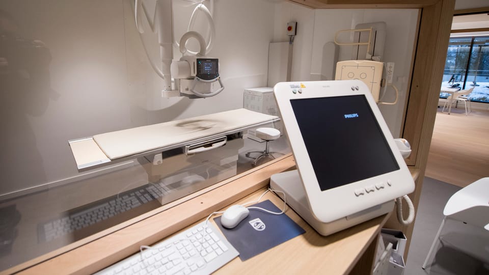 Ein Behandlungstisch mit technischen Geräten und einem Computerbildschirm. 