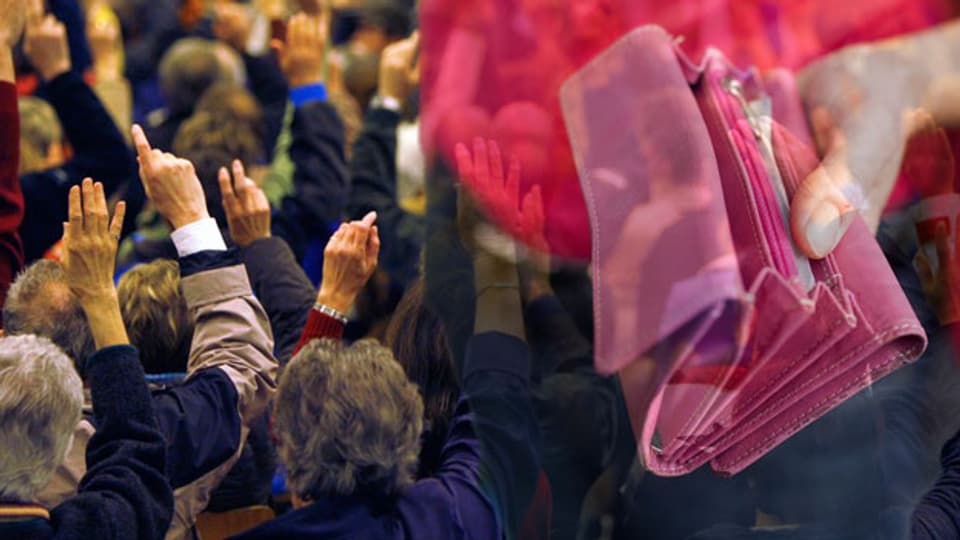 Menschen an einer Gemeindeversammlung heben die Hand zur Abstimmung, im Vordergrund ein Geldbeutel (Montage).