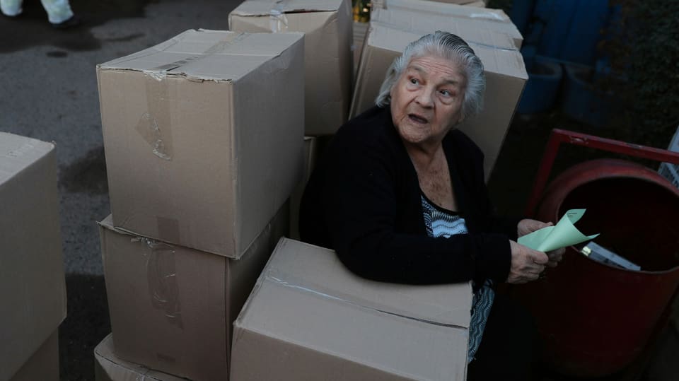Eine Frau in Santiago sitzt zwischen Lebensmittelpaketen der Regierung.