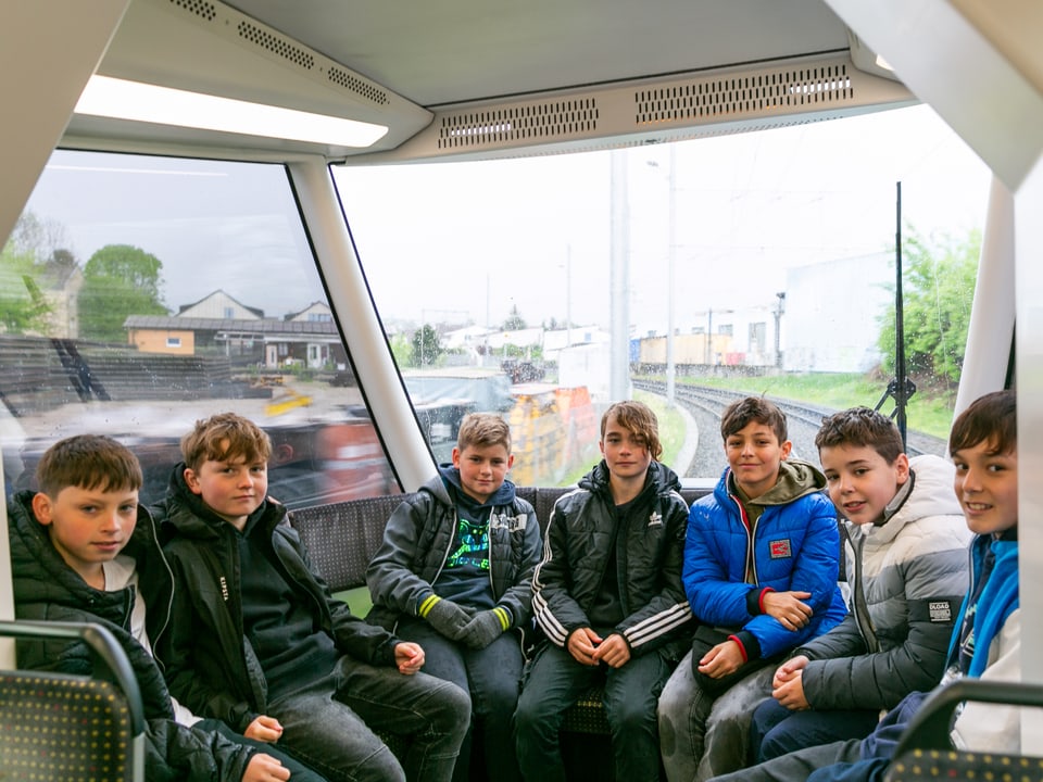 Eine Gruppe Jungs sitzt ganz hinten in einer Sitzecke im Tram.