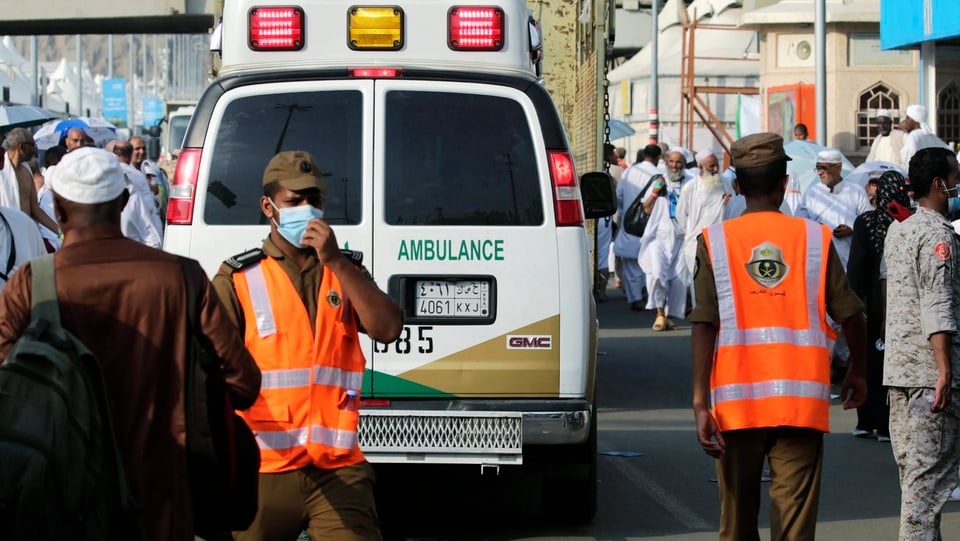 Ein Uniformierter mit Schutzmaske steht vor einem Ambulanzfahrzeug.
