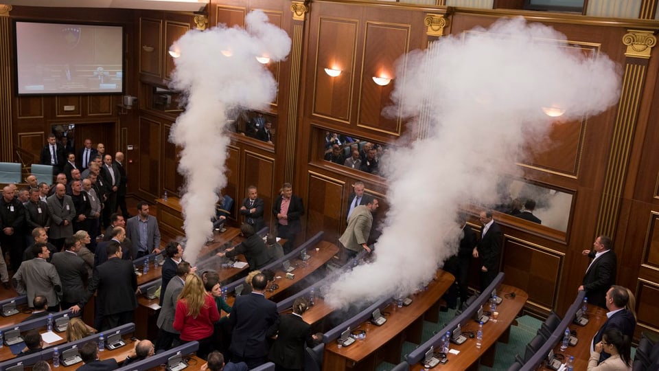 Zwei Tränengaswolken strömen in Sitzreihen des Parlamentes aus.