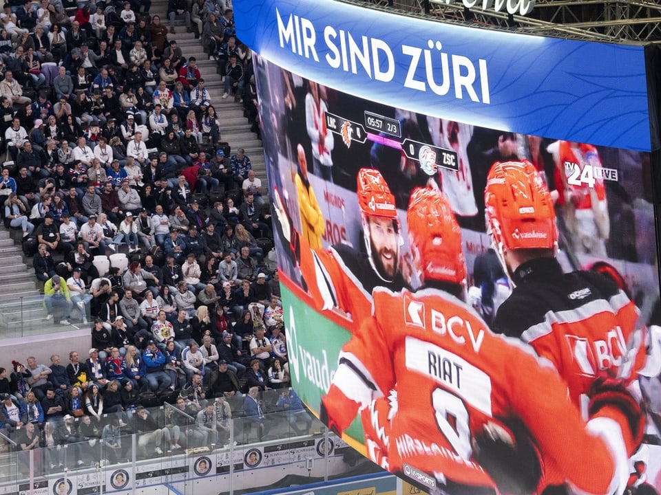 Eishockeyspieler feiern ein Tor auf einer Anzeigetafel vor Zuschauern.