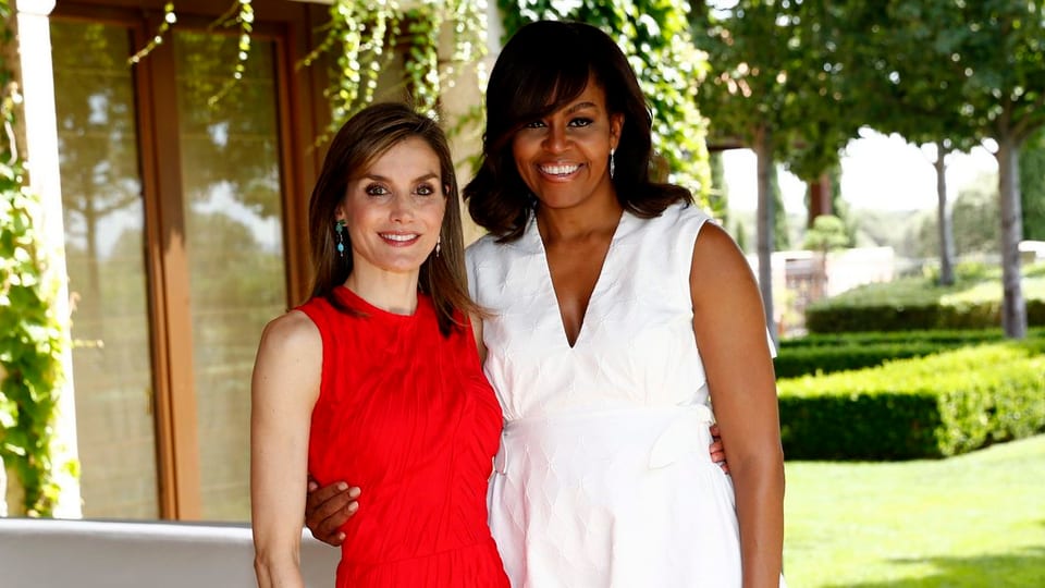 Königin Letizia im roten Kleid posiert neben Michelle Obama, die ein weisses Kleid trägt. 