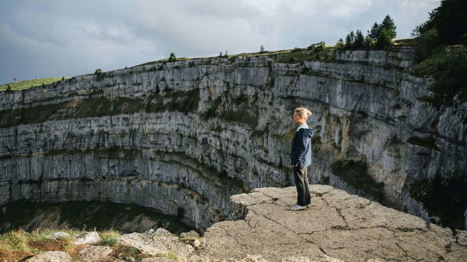 Eine Frau steht am Rand über einer steil abfallenden Felswand