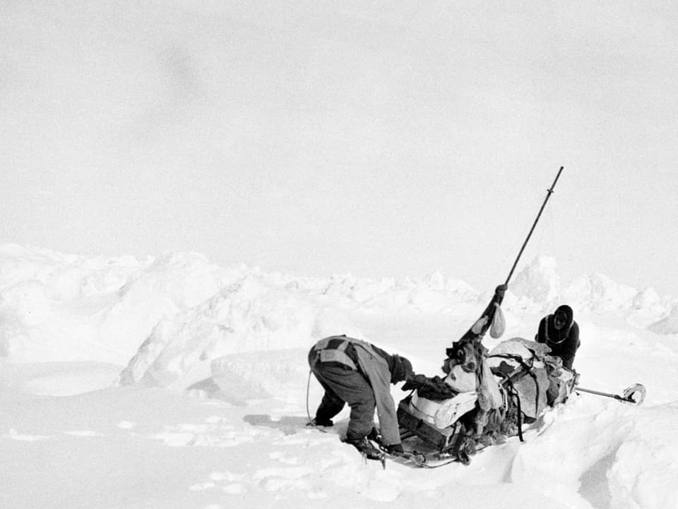 Ein Schlitten und zwei Expeditionsteilnehmer im Schnee.