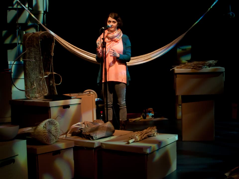 Aninna Polivka inmitten des Bühnenbildes mit Archivschachteln und einer Hängematte