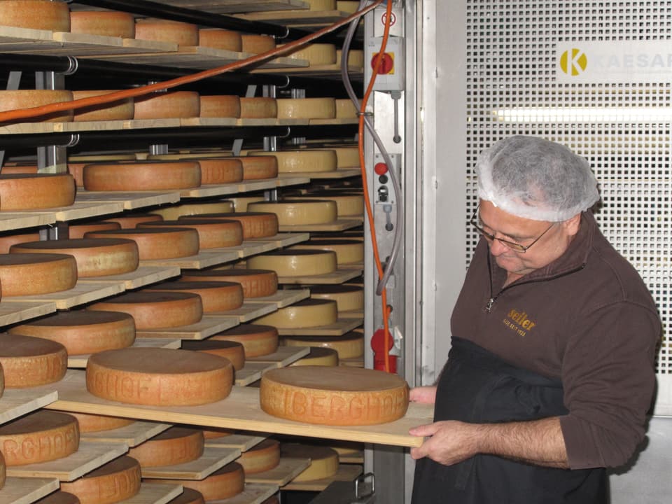 Ein Angestellter prüft den reifenden Käse.