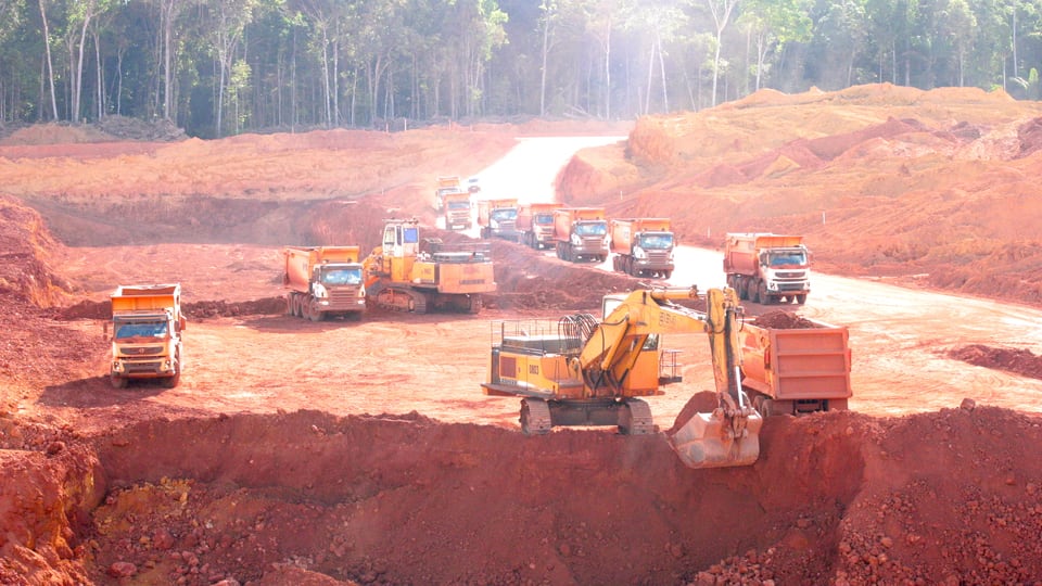 Lastwagen und Bagger beim Abbau von Bauxit-Erz im brasilianischen Regenwald.