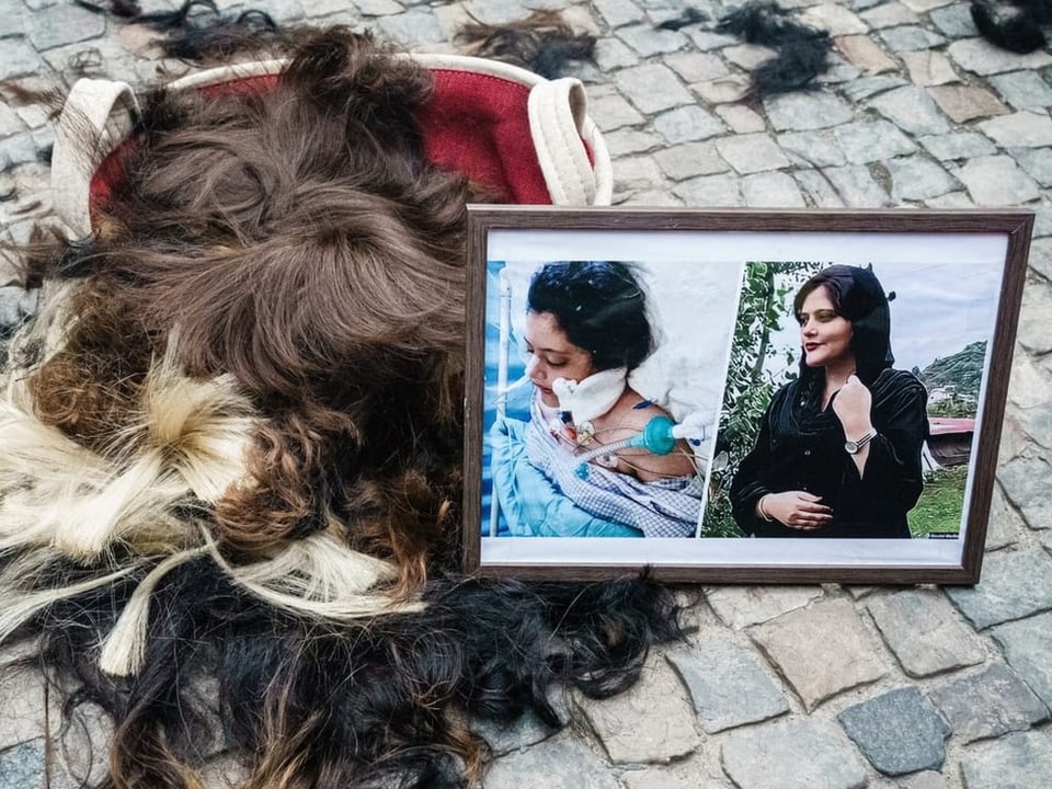 Zwei Bilder mit Amini – einmal normal und einmal im Spital – wurden auf den Boden gestellt, auf abgeschnittene Haare. 