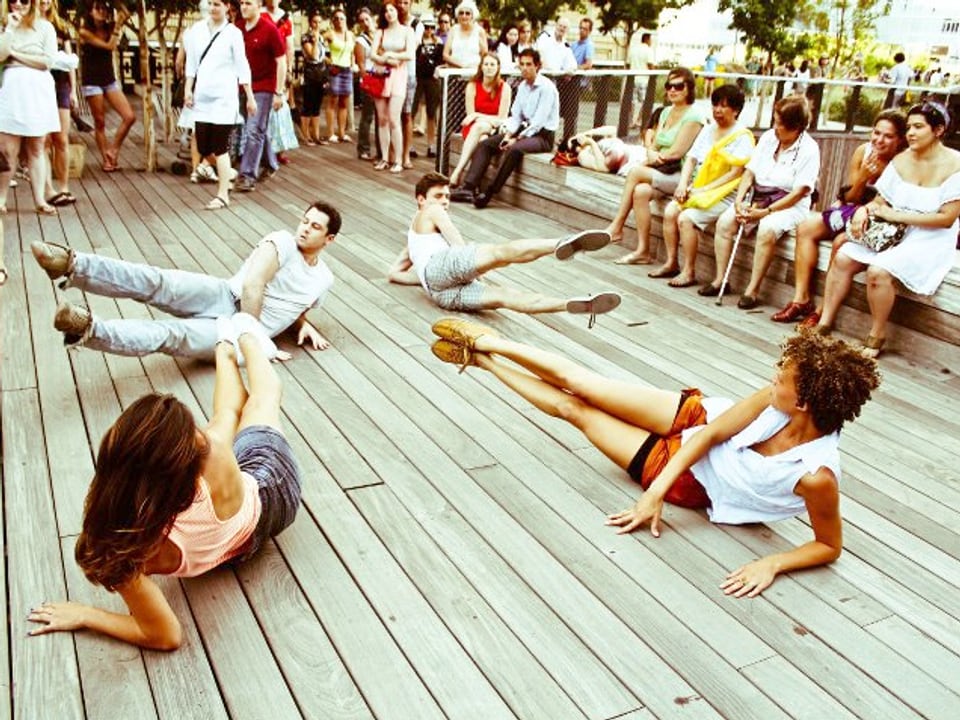 Menschen strecken ihre Beine auf einer Holzunterlage.