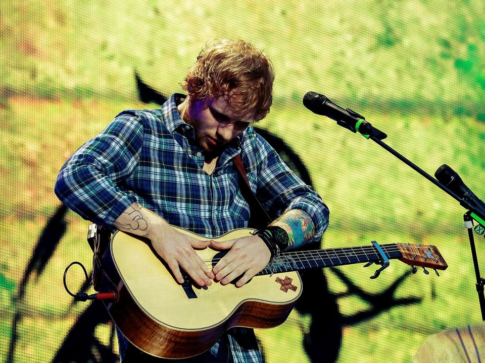 Ed Sheeran trommelt auf seiner Gitarre.