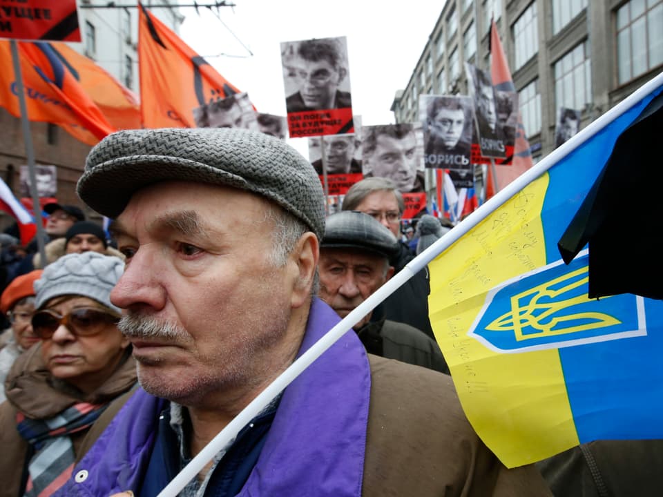 Ein Mann mit einer ukrainischen Flagge unter den Trauernden.
