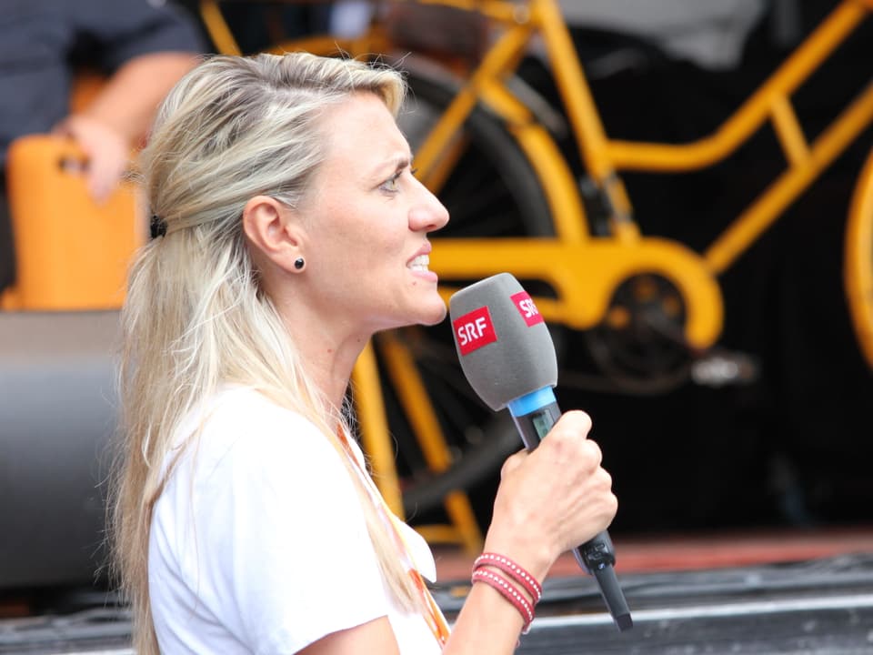 Moderatorin Sandra Schiess im Profil und Mikrofon in der Hand auf der Bühne. 
