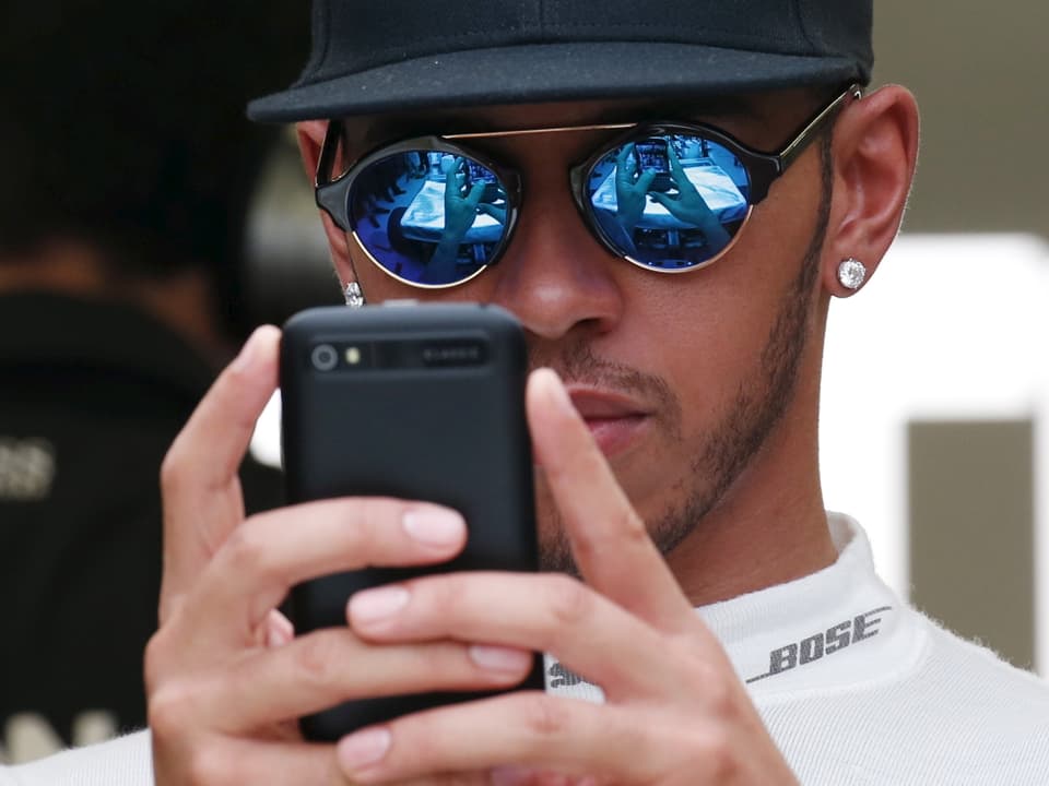 Lewis Hamilton tippt in sein Handy.