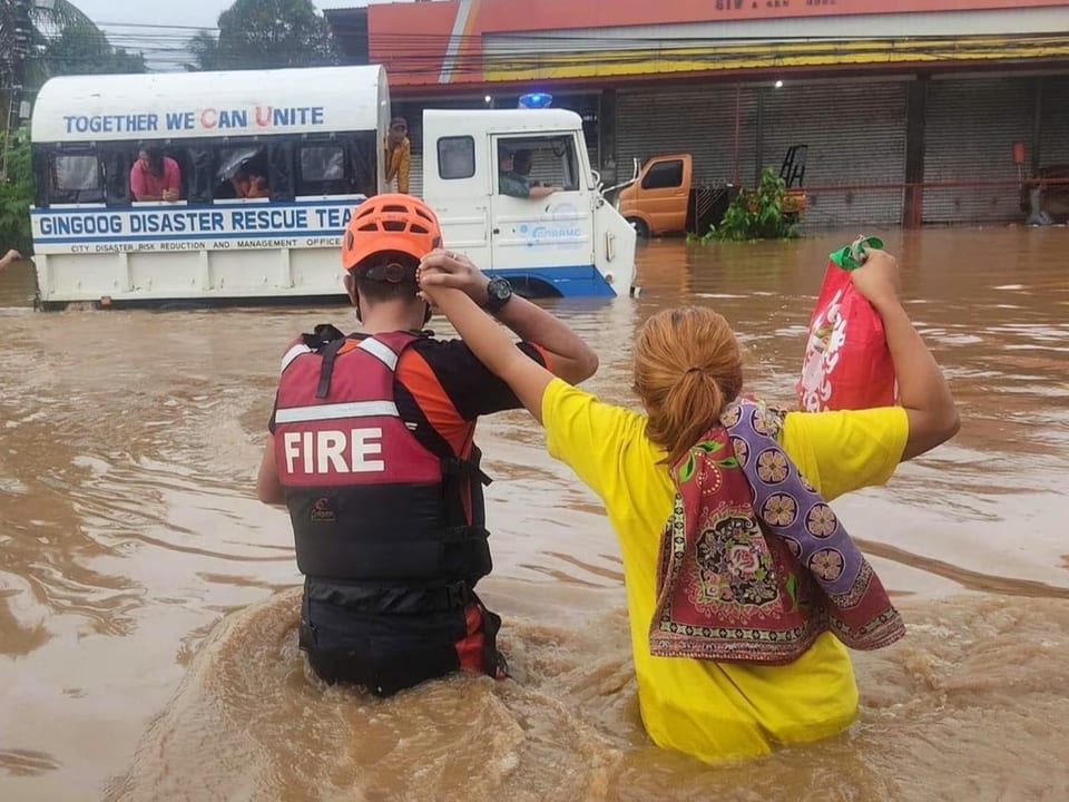 Frau wird von Rettungsdienst durchs Hochwasser geführt