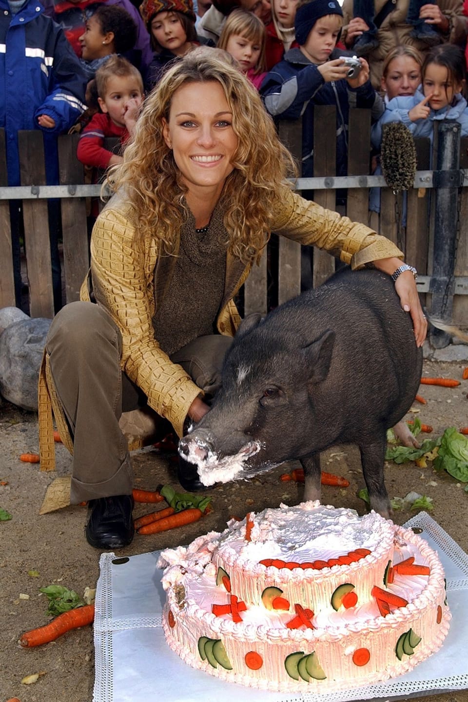Christina Surer mit einem ihrer unterdessen verstorbenen Hängebauchschweine, das eine Torte isst.