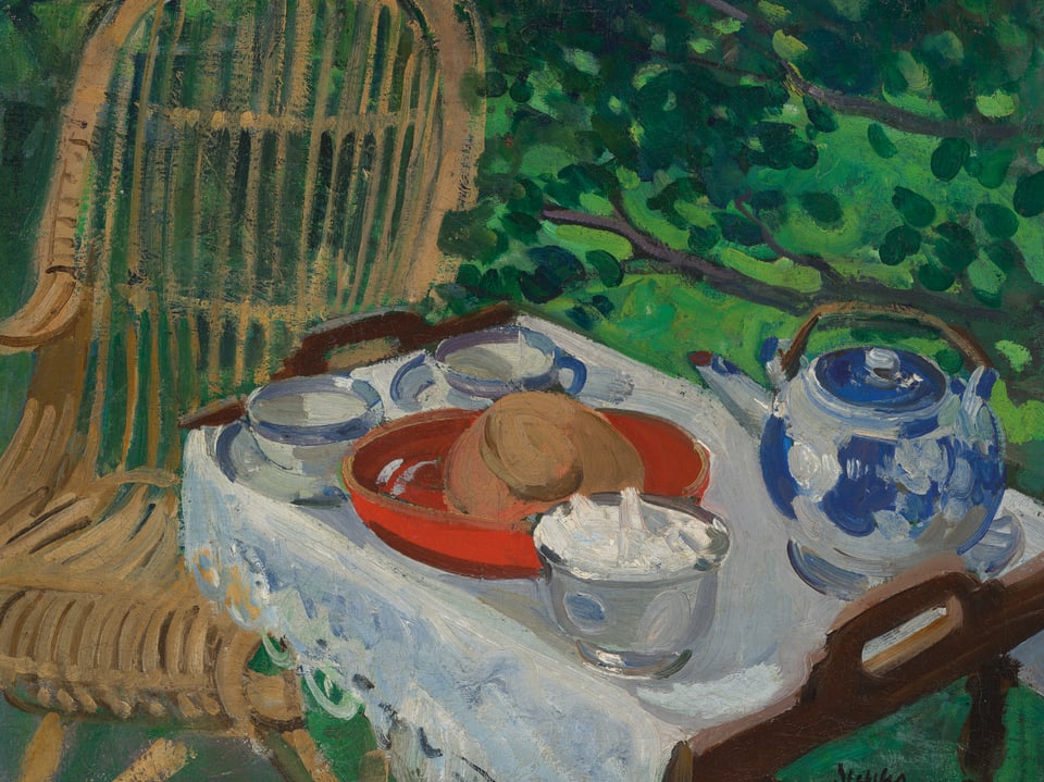 Im Schatten im Garten steht ein Tisch, darauf eine Teekanne und Gebäck. 