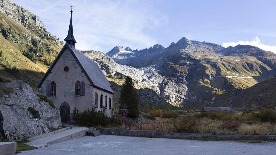 Eine historische Kirche mit Bergen im Hintergrund.