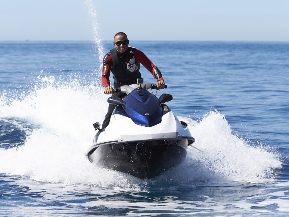 Lewis Hamilton rast mit einem Jet-Ski über das Wasser.