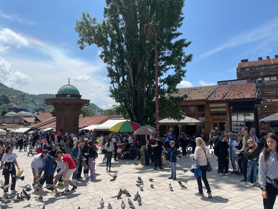 Menschen bevölkern den Platz rund um den Brunnen Sebilj in Sarajevo.