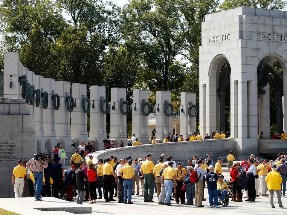 Männer stehen vor einem grossen, halbrunden, steineren Denkmal in Washington.