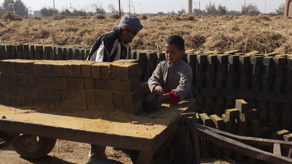 Ein Kind und ein mann bauen eine Mauer aus Ziegelsteinen