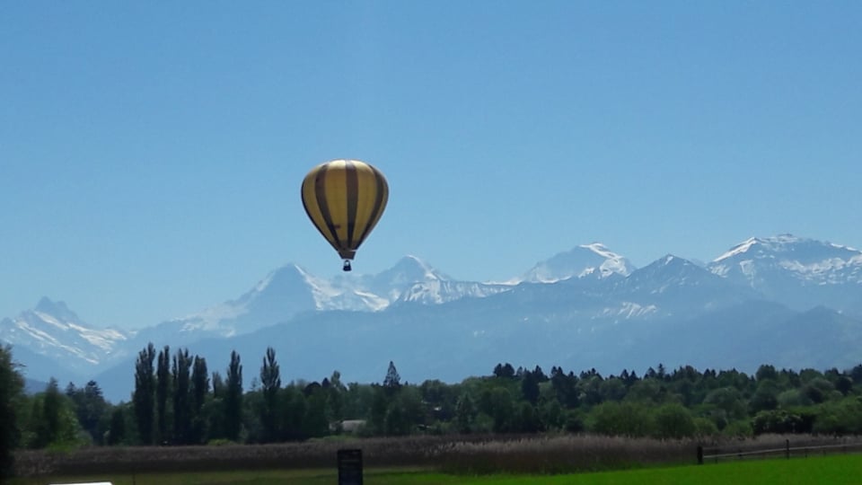 Der Himmel ist strahlen blau, die Berge des Berner Oberlandes noch tief verschneit. Ein Heissluftballon steigt gerade in den Himmel.