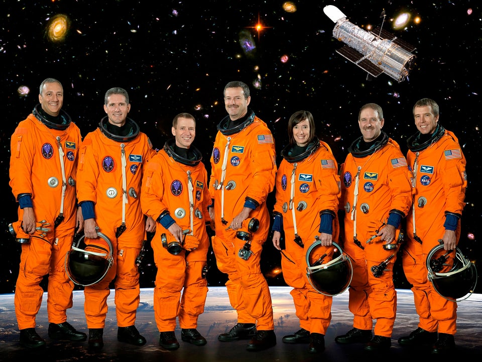 Sieben Astronautinnen und Astronauten posieren in der Schutzkleidung nebeneinander.