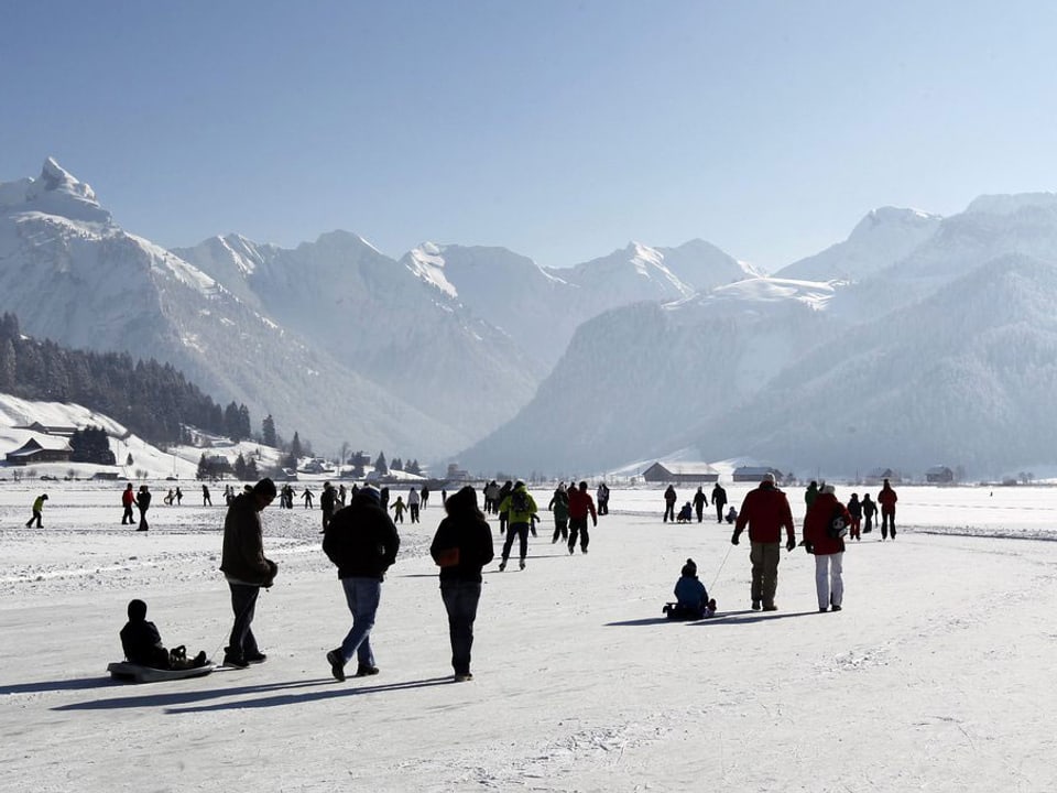 Menschen begehen den gefrorenen Sihlsee im Kanton Schwyz bei strahlendem Sonnenschein. (keystone)