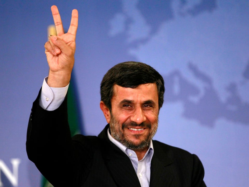 Ahmadinedschad mit Bart macht das Victory-Zeichen und lacht.