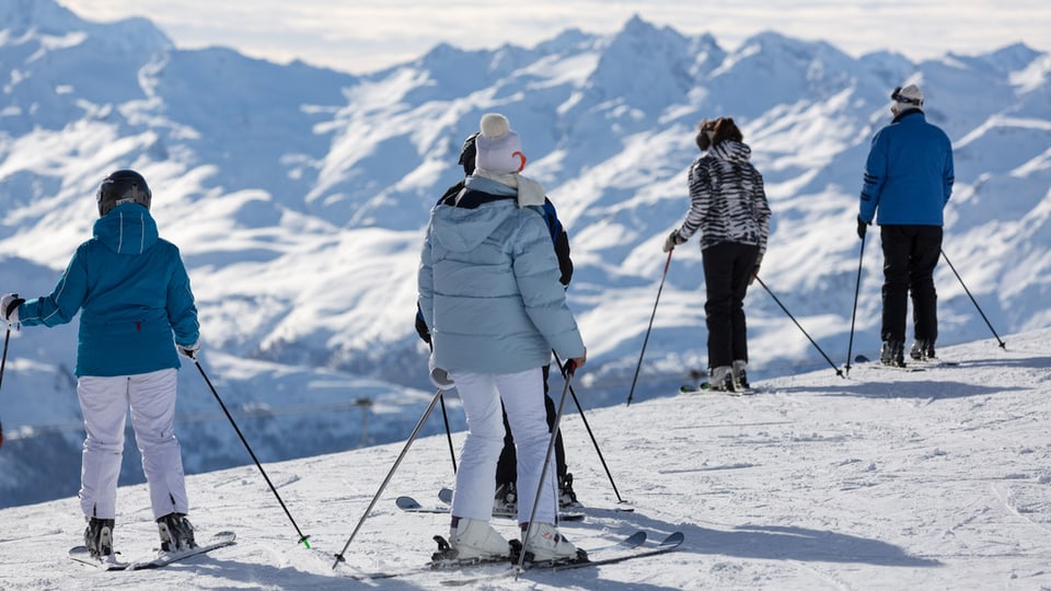 Skifahrer blicken auf die verschneite Bergwelt des Oberengadins.