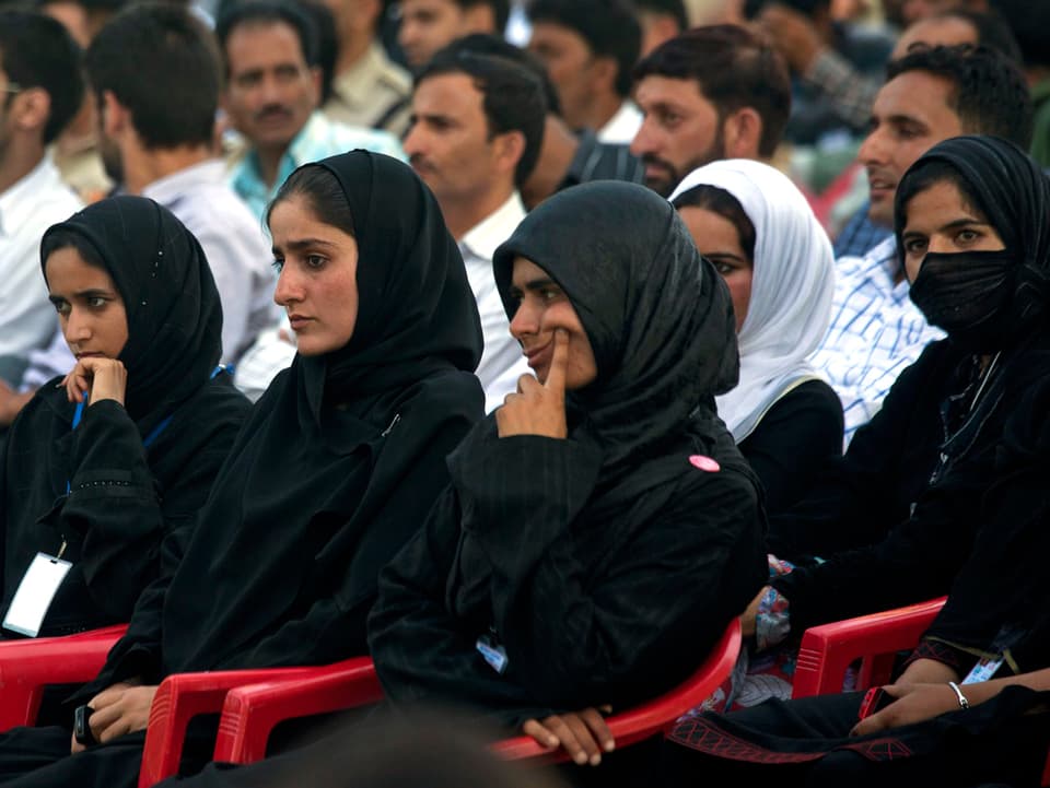 Musliminnen mit Kopftüchern hören das Konzert.
