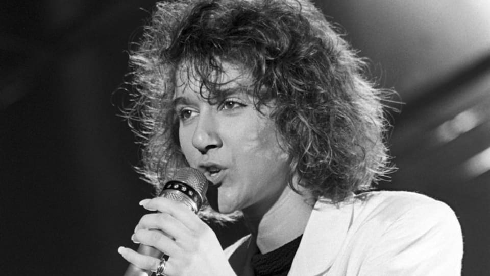 Schwarz-Weiss-Foto einer Frau mit Mikrofon, die auf der Bühne singt.