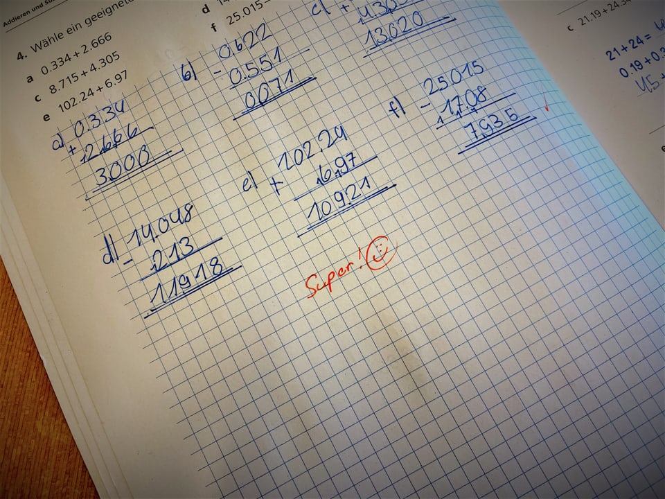 Eine Seite in einem Schulbuch, unter handgeschriebenen Mathematikrechnungen steht in roter Schrift: Super!