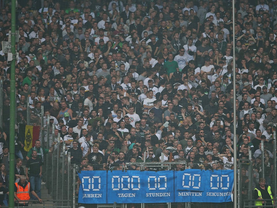 Die mitgereisten Gladbach-Fans giessen mit einem Transparent, auf dem die abgelaufene HSV-Stadionuhr zu sehen ist, weiter Öl ins Feuer.