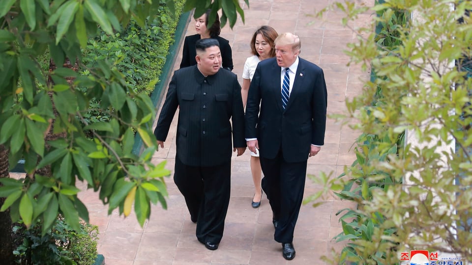 Trump und Kim gehen nebeneinander und sprechen zusammen.