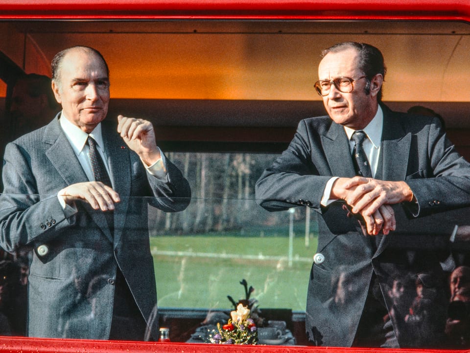 Zwei Politiker schauen aus einem Zugsfenster.
