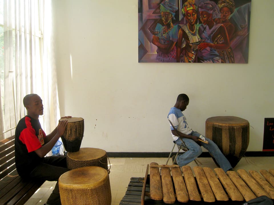 Der Museumsguide mit seinem Kollegen in der Musizierecke bei ugandischen Trommeln und Xylophon.