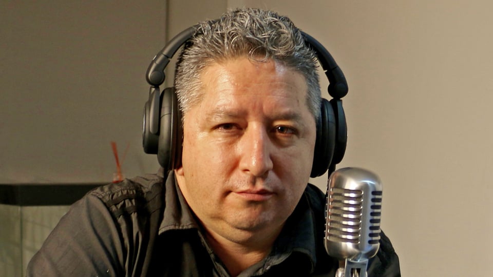 Herbin Hoyos mit Kopfhörer vor einem Mikrofon.