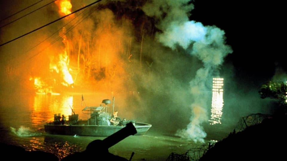 Kriegsszene aus einem Film mit Booten, Explosion und Rauch in der Nacht.