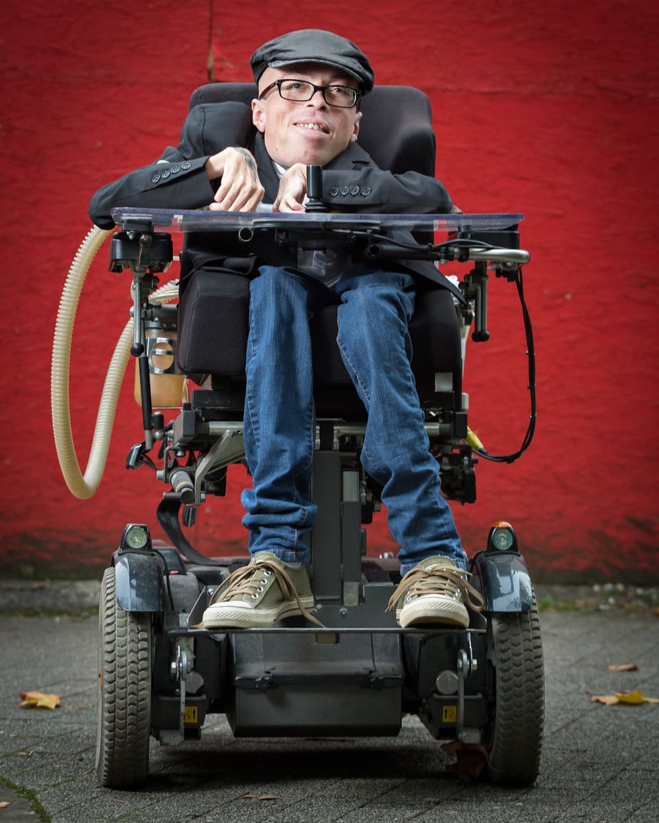 Mann im Rollstuhl vor roter Wand