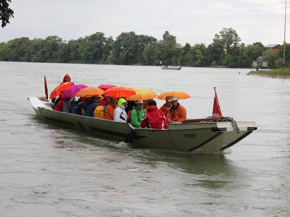 Wandergruppe mit Schirmen im Boot auf dem Fluss.