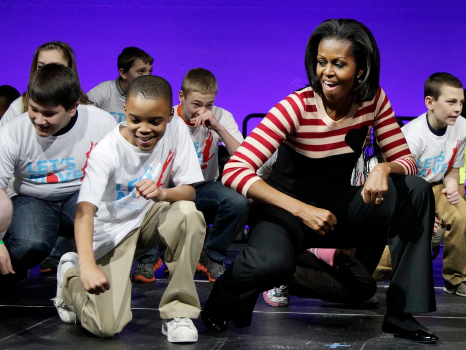 Michelle Obama tanzt mir einer Gruppe Jugendlicher einen Hip-Hop-Move.