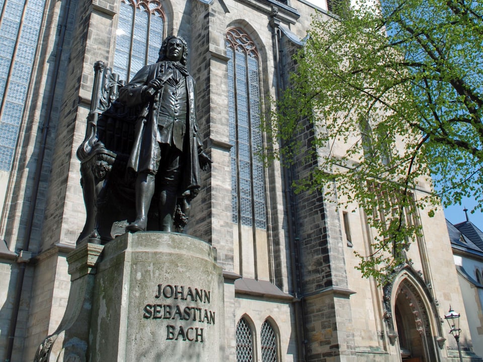 Eine Statue eines Mannes (Bach) vor einer Kirche.