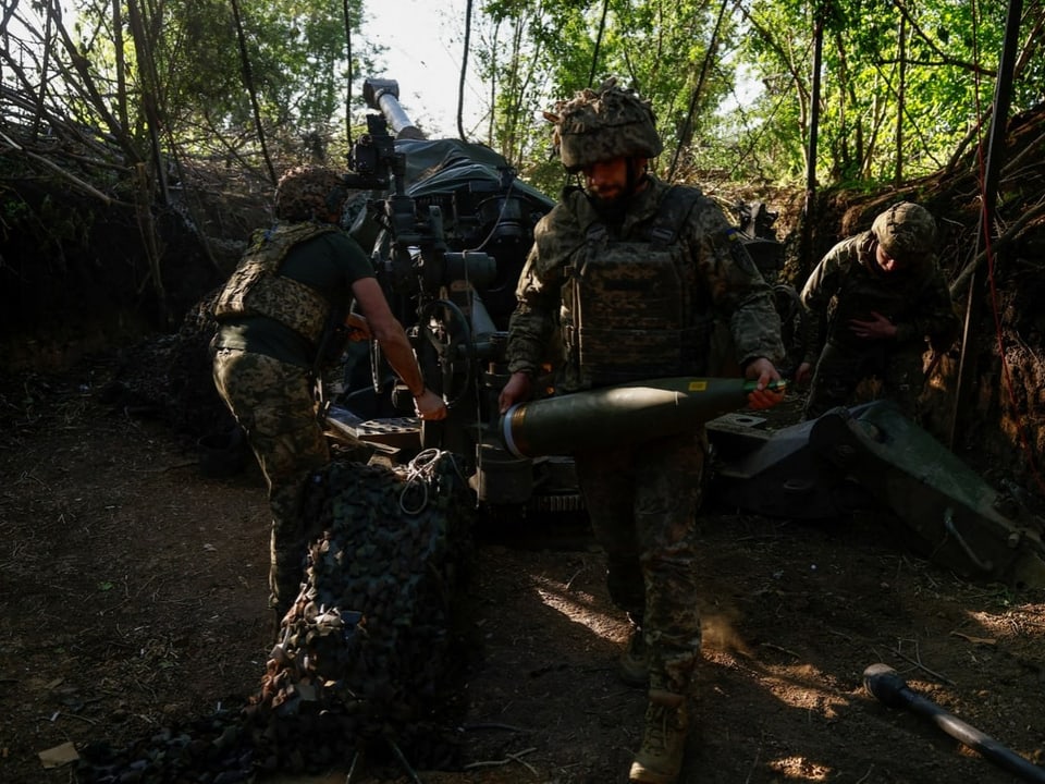 Soldaten laden Granate in eine Haubitze in einem Wald.