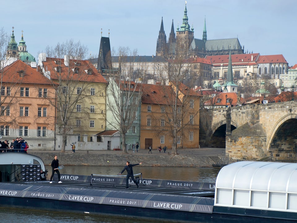 Federer und Berdych spielen auf einem Schiff vor der Prager Burg und der Karlsbrücke Tennis.