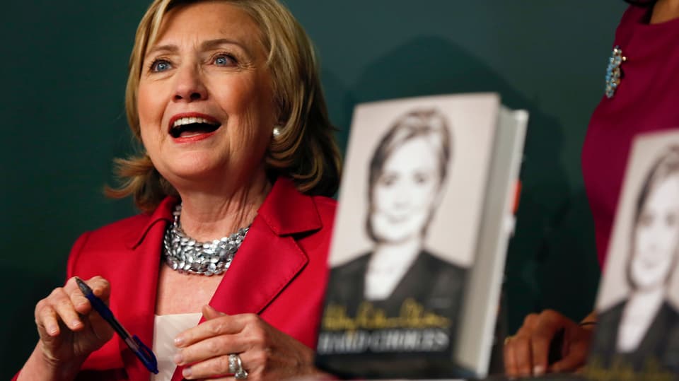 Clinton lachend mit einem Buch im Vordergrund.
