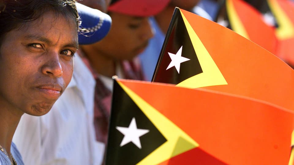 Unabhängigkeitsfeier in Osttimor im Jahr 2002: Menschen halten die Flagge.